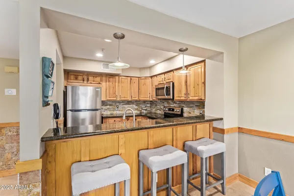 a kitchen with stainless steel appliances kitchen island granite countertop a table and chairs in it