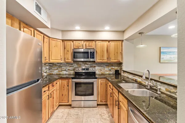 a kitchen with stainless steel appliances granite countertop a sink stove microwave and refrigerator