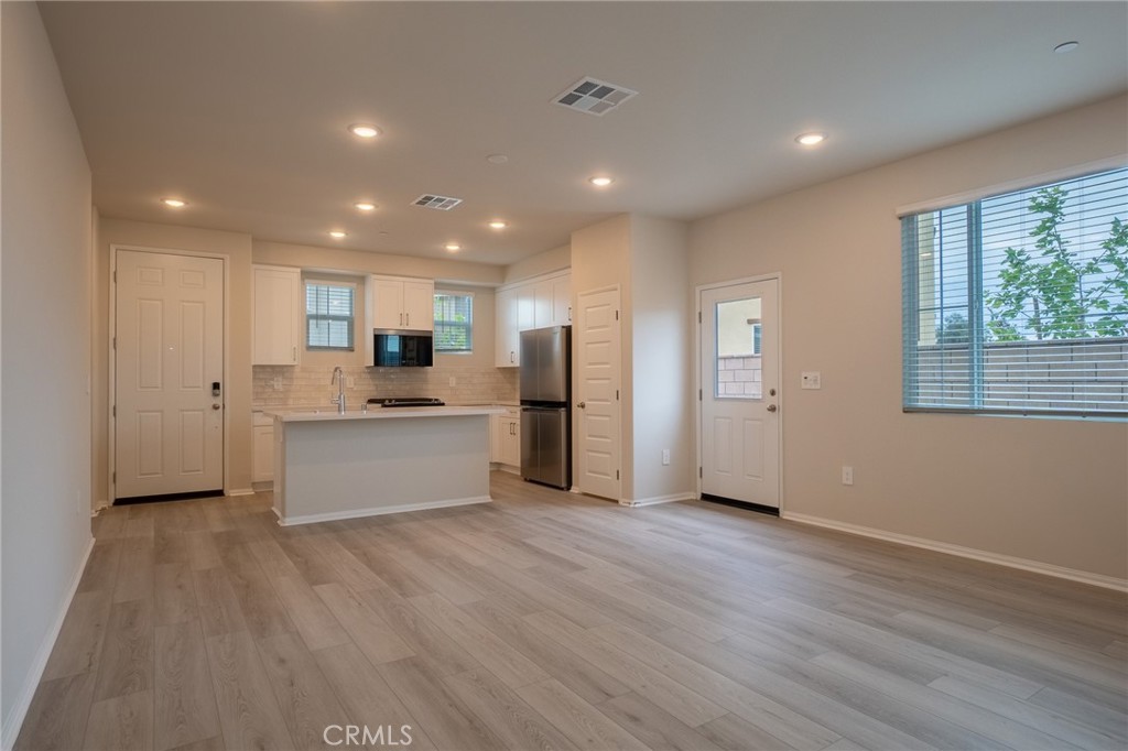 28586 Via Roble Temecula, CA 92591 - Photo 5 of 18 a view of kitchen with granite countertop refrigerator oven sink and white cabinets with wooden floor