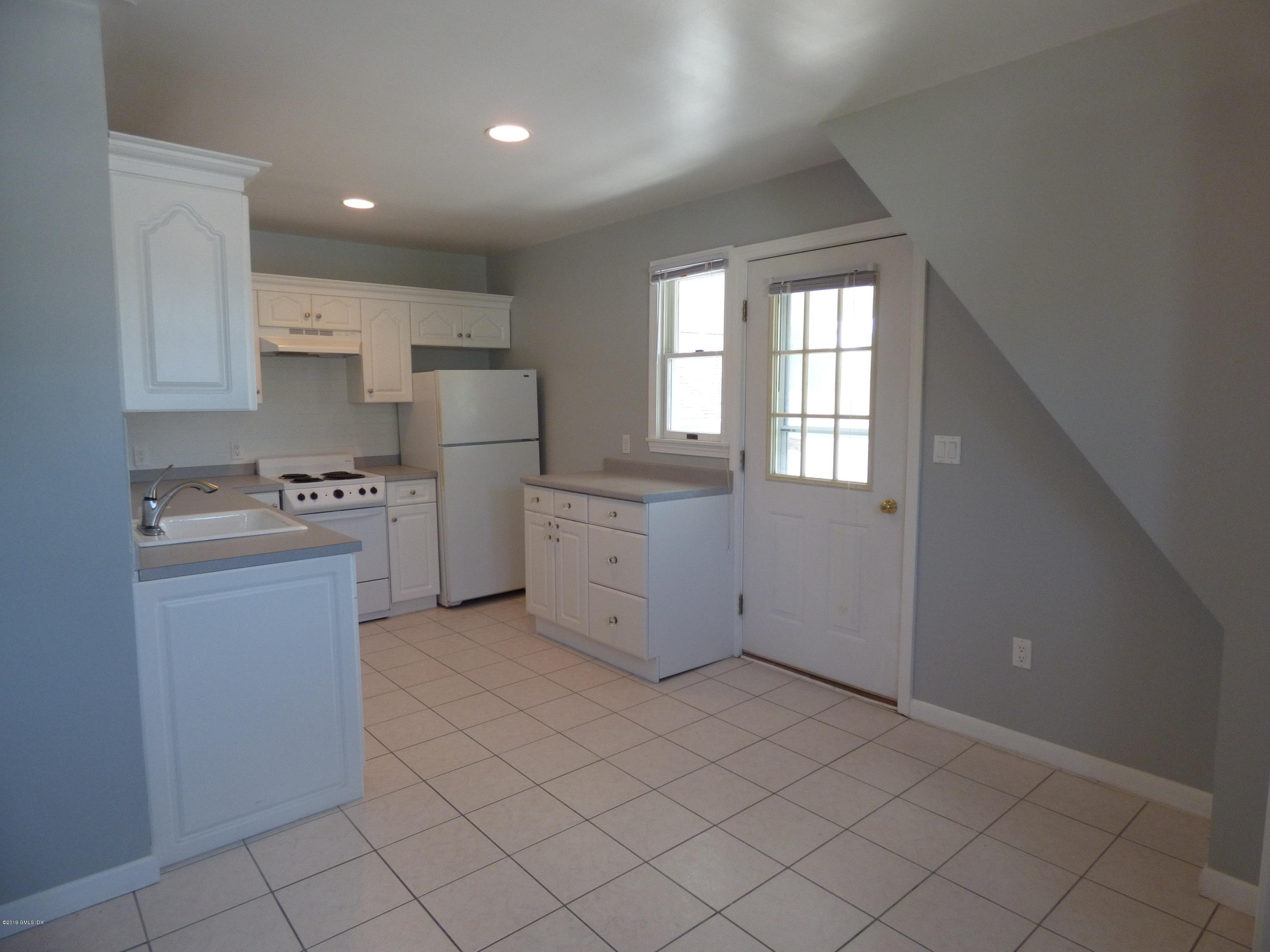 16 Lexington Avenue, Unit UPSTAIRS Greenwich, CT 06830 - Photo 4 of 12 a kitchen with a refrigerator and white cabinets