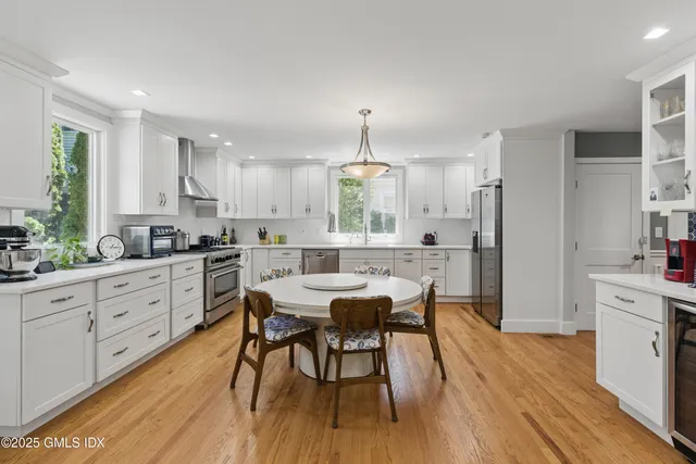 a kitchen with granite countertop stainless steel appliances white cabinets and wooden floor