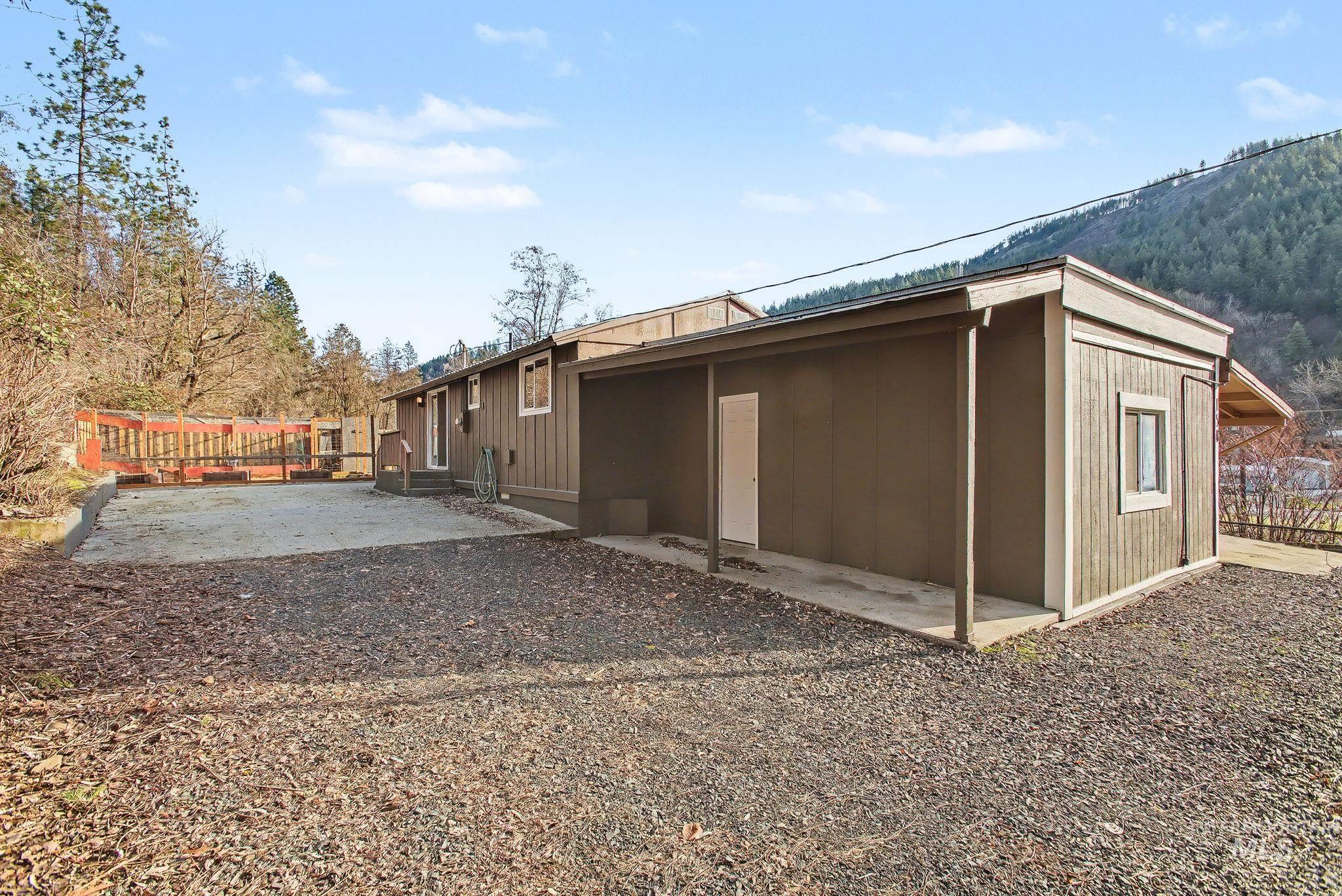 150 Elm Street Orofino, ID 83544 - Photo 27 of 36 Mountain backdrop with a brown exterior property featuring a covered patio, additional detached structure with a window, and a wood-decked outdoor area