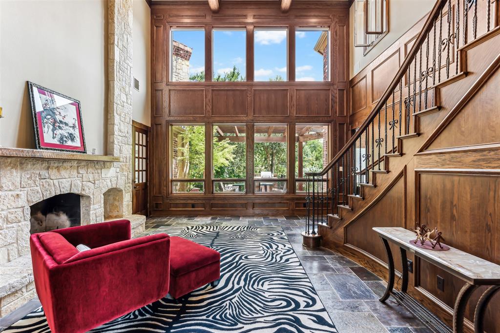 1815 West Forest Grove Road Lucas, TX 75002 - Photo 9 of 40 Living area featuring stone tile floors, wooden walls, a fireplace, stairs, and a towering ceiling