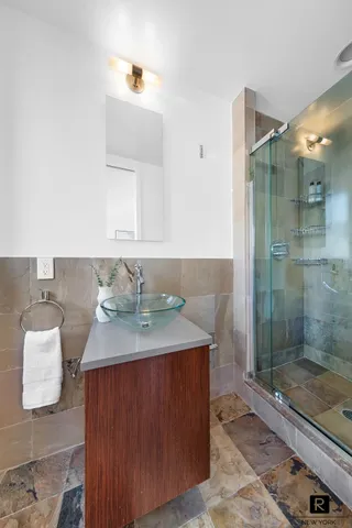 a bathroom with a granite countertop sink a mirror and shower
