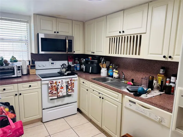 a kitchen with white cabinets and appliances
