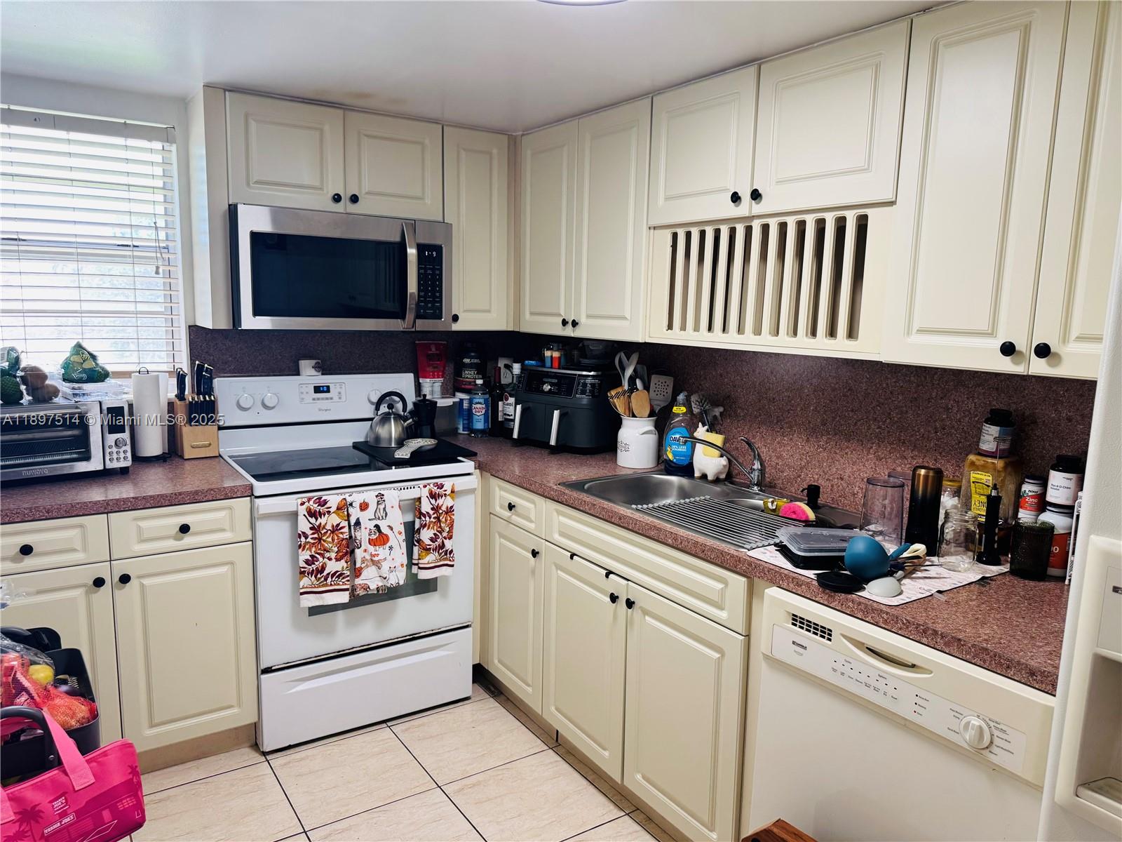 502 Northwest 87th Avenue, Unit 302 Miami, FL 33172 - Photo 9 of 12 a kitchen with white cabinets and appliances
