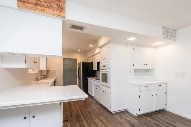 a large white kitchen with a lot of counter space and wooden floor