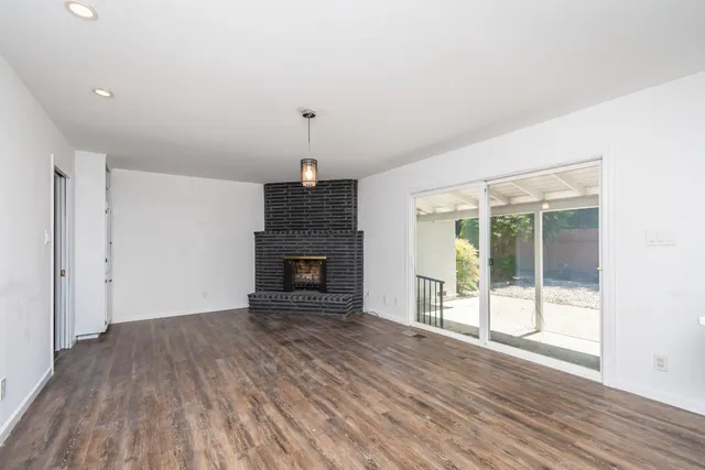 a view of empty room with wooden floor and fireplace
