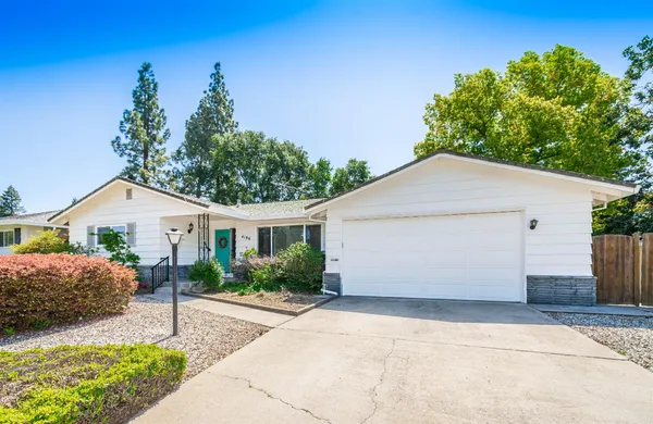 a front view of house with yard and trees in the background