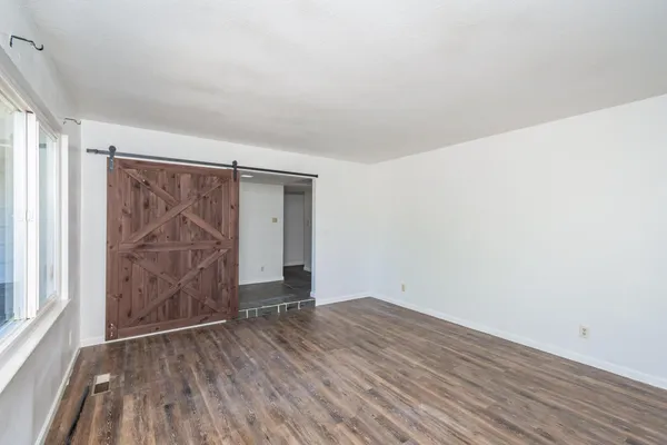 a view of an empty room with wooden floor and a window