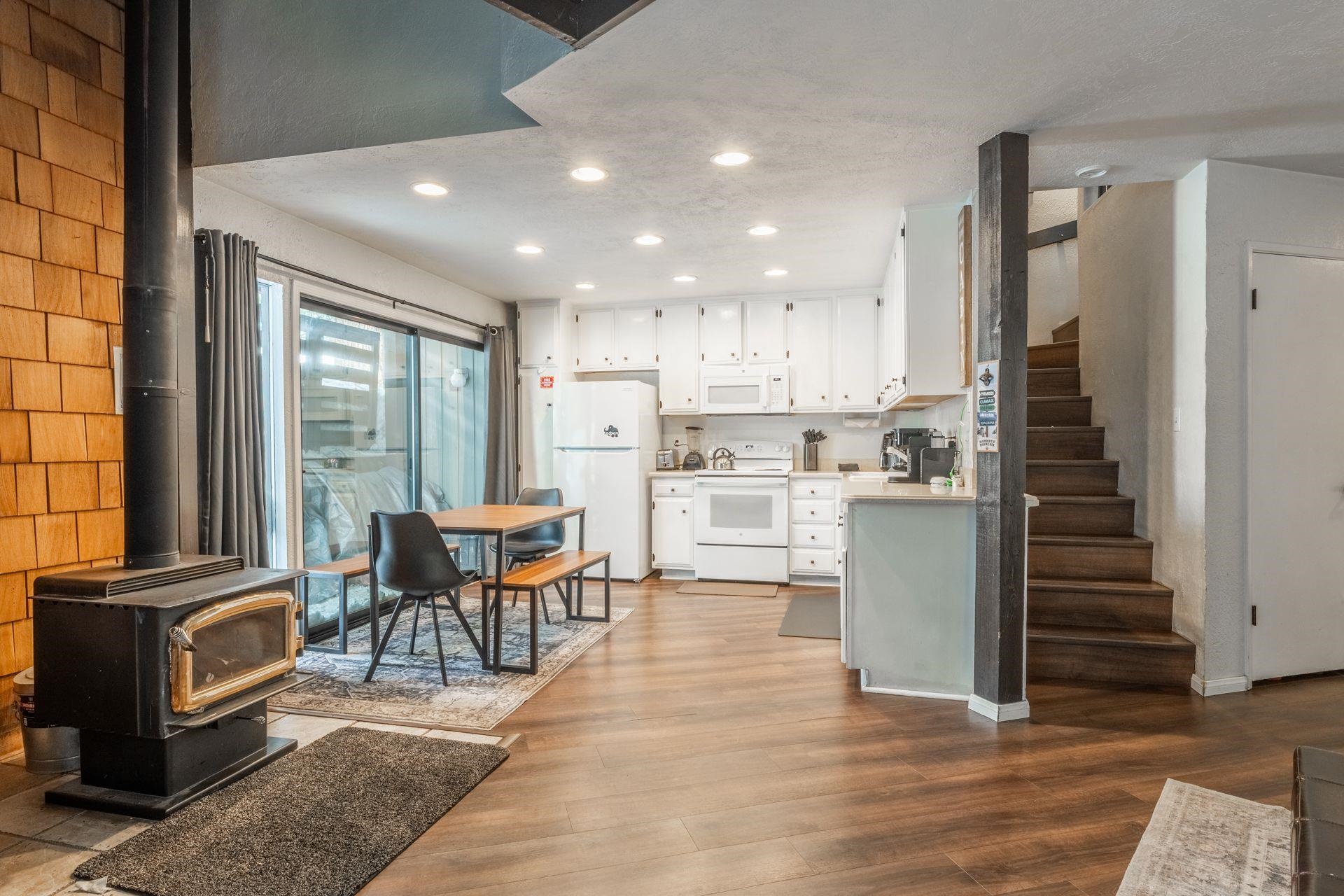 286 Old Mammoth Road, Unit 71 Mammoth Lakes, CA 93546 - Photo 6 of 24 Kitchen with white cabinets, white appliances, light countertops, a wood stove, and light wood-style floors