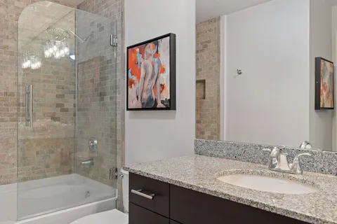 a bathroom with a granite countertop sink a mirror and a bathtub