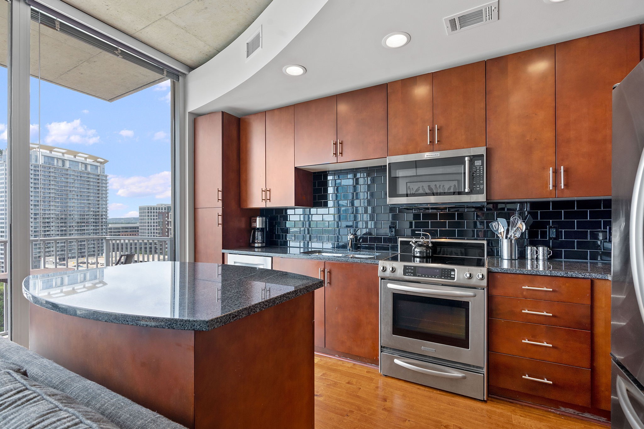 360 Nueces Street, Unit 1310 Austin, TX 78701 - Photo 9 of 40 a kitchen with kitchen island granite countertop wooden cabinets a stove and a sink