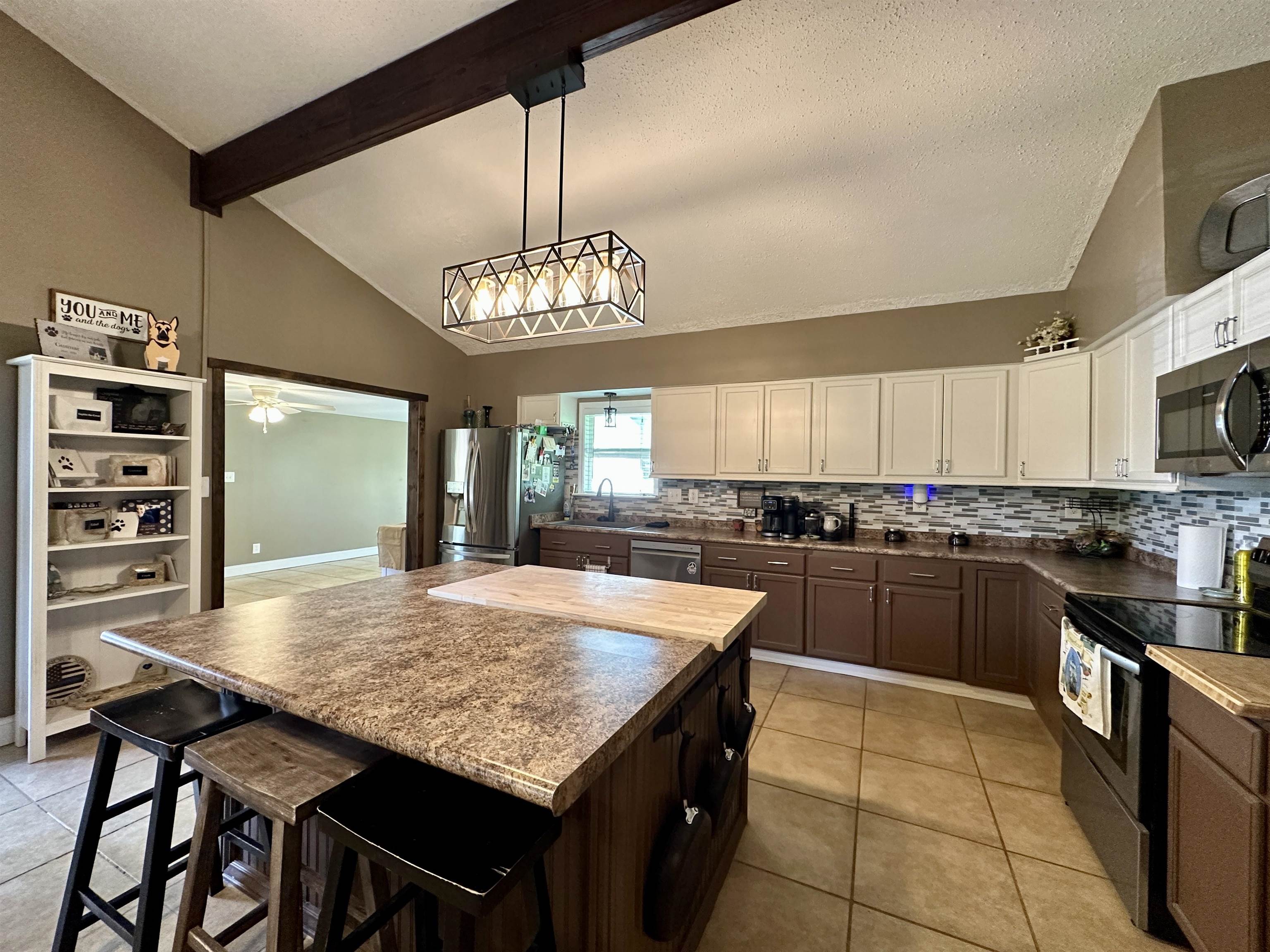 1230 Joann Road Somerville, TN 38068 - Photo 10 of 29 Kitchen featuring a vaulted ceiling with exposed wood-finish beam, central island with a wood-finish countertop, two-tone cabinetry, tiled backsplash, and stainless steel appliances