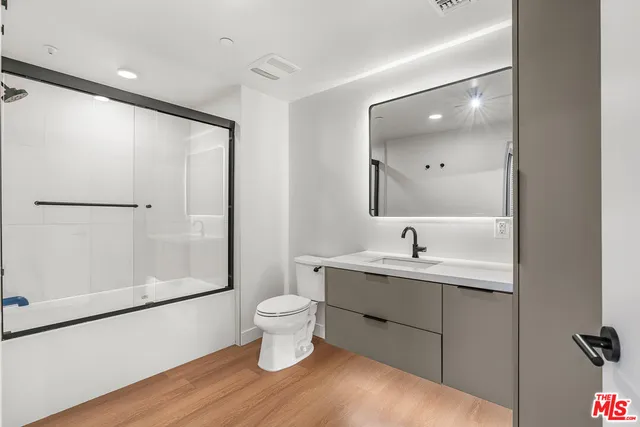 a spacious bathroom with a granite countertop sink toilet a mirror and shower