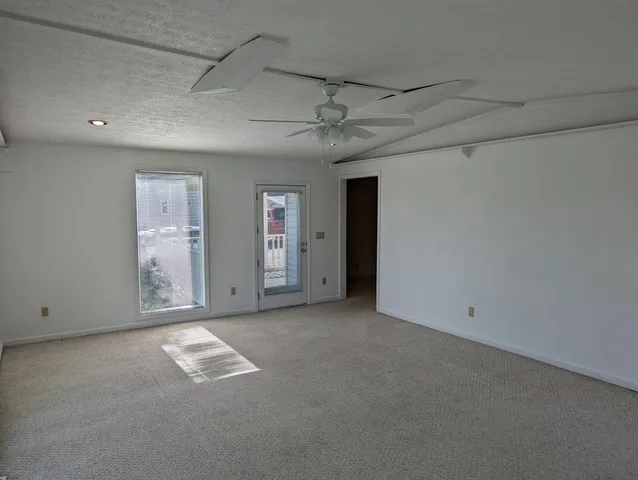 a view of an empty room with wooden floor and window