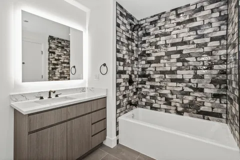 a bathroom with a bathtub sink vanity and mirror