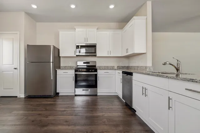 a kitchen with white cabinets and stainless steel appliances