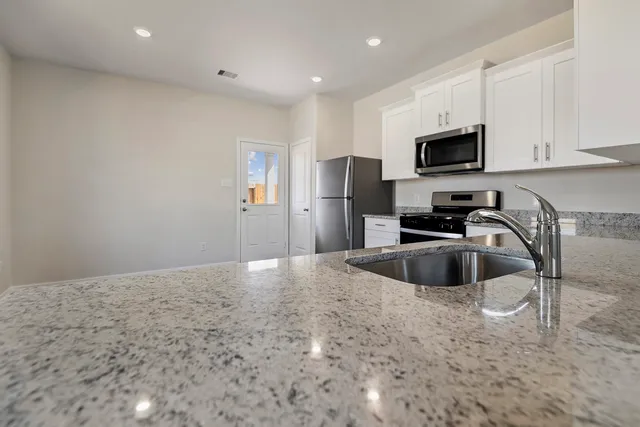 a kitchen with granite countertop a refrigerator sink and microwave