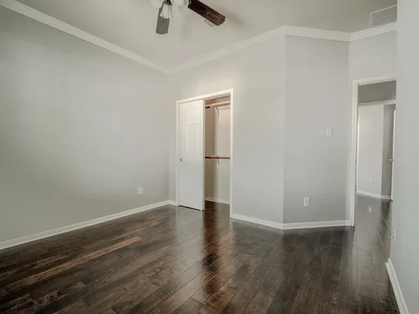 an empty room with wooden floor cabinet and windows