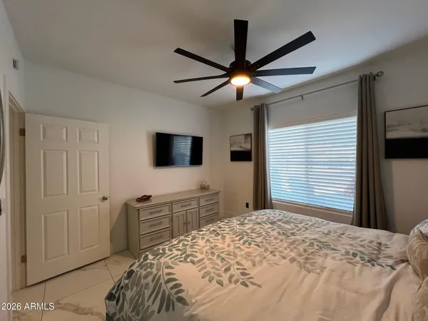 a bedroom with a bed and a flat tv screen on dresser