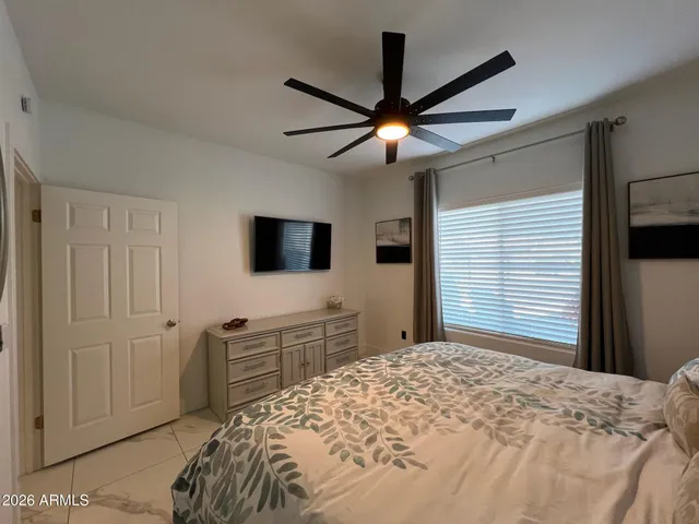 a bedroom with a bed and a flat tv screen on dresser