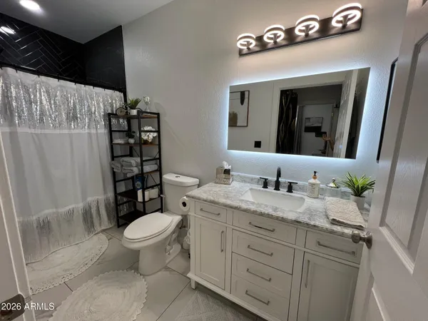 a bathroom with a granite countertop sink toilet and mirror