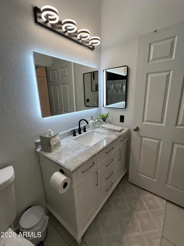 a bathroom with a granite countertop sink a toilet and mirror