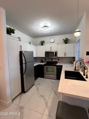 a kitchen with stainless steel appliances kitchen island granite countertop a refrigerator a sink a stove with white cabinets