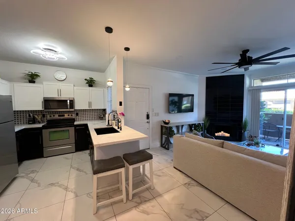 a living room with stainless steel appliances kitchen island granite countertop a stove a sink a refrigerator and a black cabinets