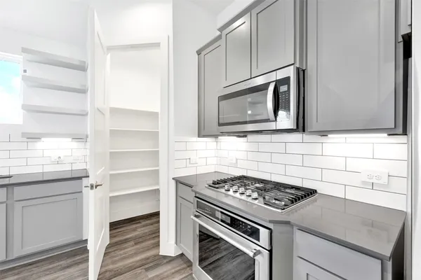 a kitchen with stainless steel appliances kitchen island wooden floors and white cabinets