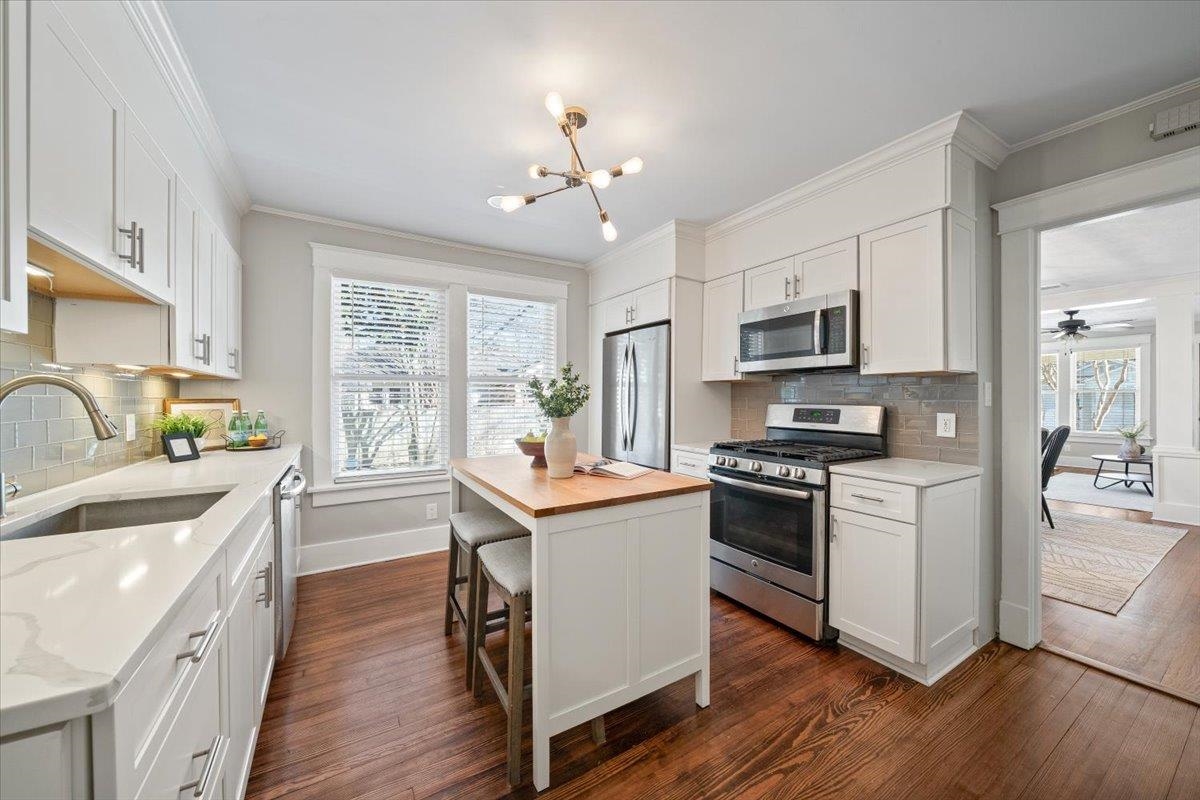 573 Alexander Street Memphis, TN 38111 - Photo 10 of 24 a kitchen with stainless steel appliances granite countertop a sink dishwasher a stove top oven a refrigerator with island and chairs with wooden floor