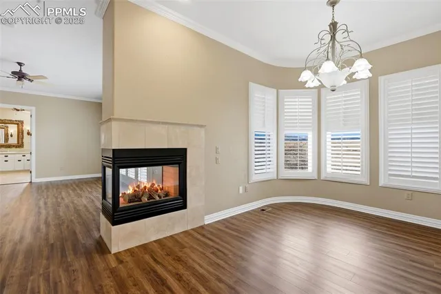 a view of an empty room with wooden floor fireplace and a window
