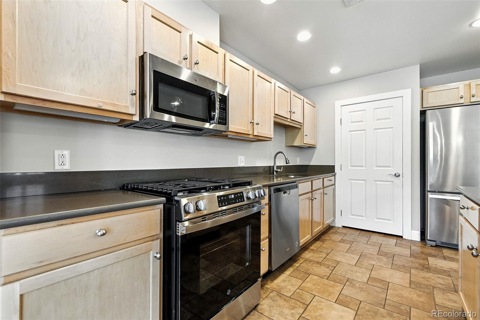1631 Emerson Street, Unit 207 Denver, CO 80218 - Photo 12 of 30 a kitchen with stainless steel appliances granite countertop a stove a microwave and a refrigerator