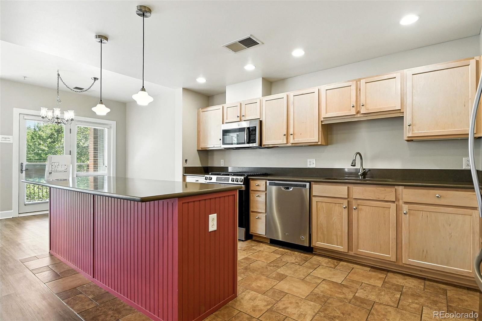 1631 Emerson Street, Unit 207 Denver, CO 80218 - Photo 9 of 31 a kitchen with kitchen island granite countertop a sink a counter space appliances and cabinets