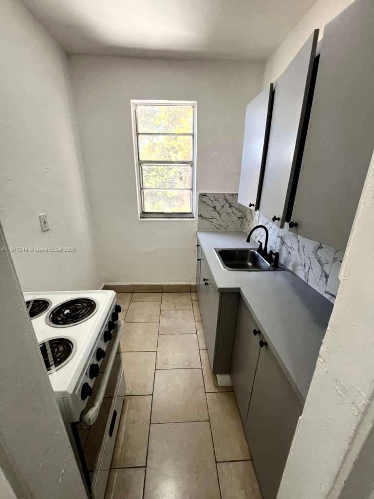 1560 Southwest 5th Street, Unit 11 Miami, FL 33135 - Photo 7 of 12 a kitchen with a sink a stove and a microwave