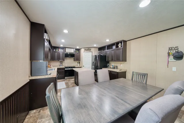 a kitchen with stainless steel appliances kitchen island granite countertop a refrigerator a stove a sink dishwasher with a dining table and chairs