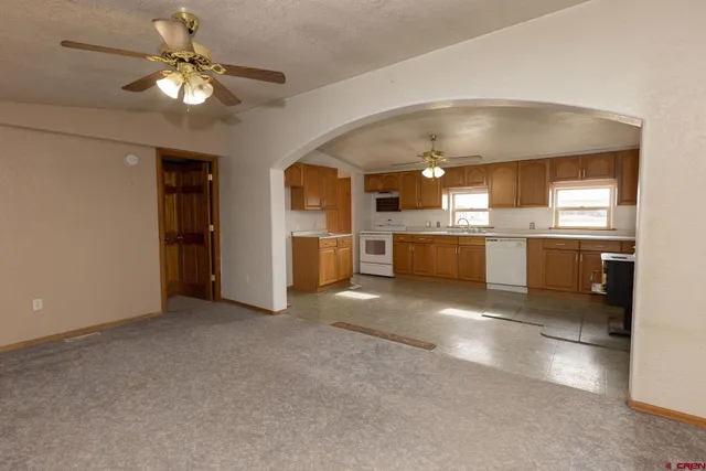 a view of a kitchen with a stove cabinets a ceiling fan and wooden floor