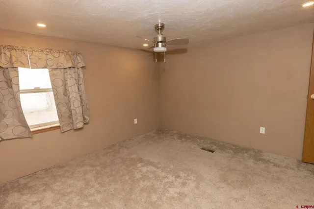 en empty room with windows and ceiling fan