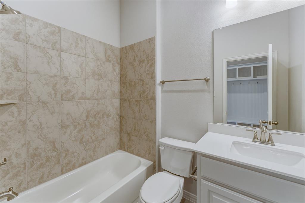 605 Tay Tay Way Springtown, TX 76082 - Photo 18 of 31 Bathroom featuring a white bathtub, beige tile surround, white vanity with integrated sink, brushed nickel faucet, and a large wall mirror