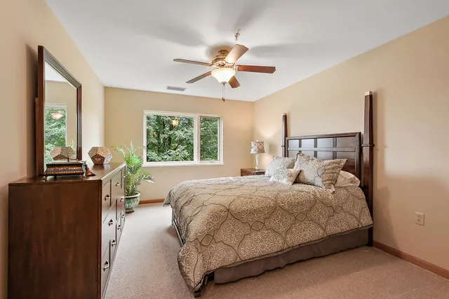 a bedroom with a large bed and a chandelier fan