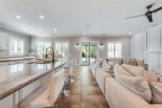 a large living room with stainless steel appliances granite countertop couches a fireplace a flat screen tv and a large window