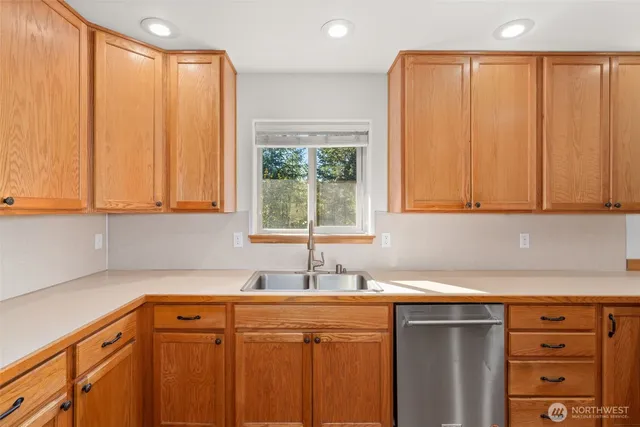 a kitchen with stainless steel appliances a sink dishwasher and cabinets with wooden floor