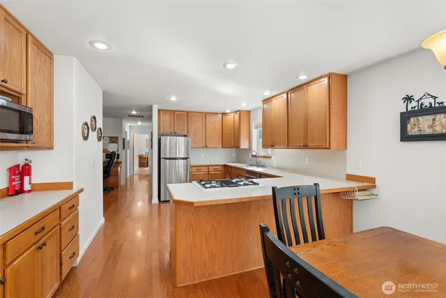 a kitchen with stainless steel appliances granite countertop a refrigerator a stove top oven a sink dishwasher and white cabinets with wooden floor