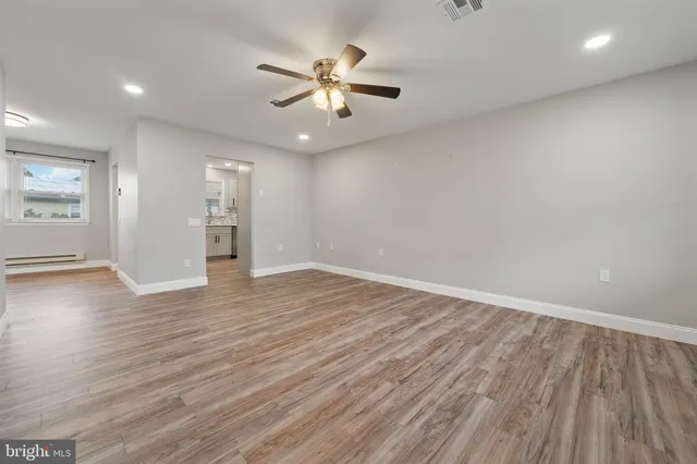 an empty room with wooden floor chandelier fan and windows