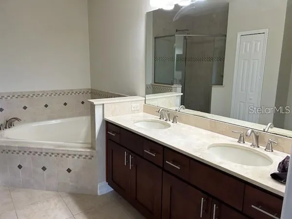 a bathroom with a granite countertop double vanity sink and mirror