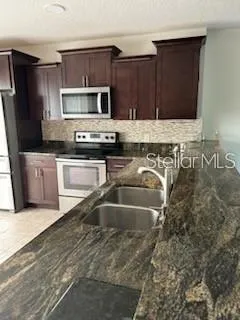a kitchen with stainless steel appliances granite countertop a sink stove and microwave