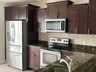 a kitchen with kitchen island granite countertop wooden cabinets and stainless steel appliances