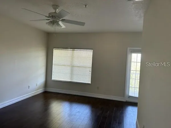 an empty room with wooden floor and windows