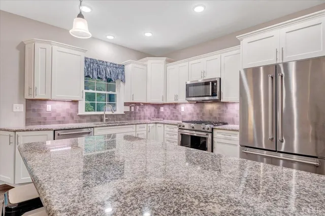 a kitchen with stainless steel appliances granite countertop a stove a sink and a refrigerator